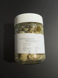 A clear glass jar of Sydney Rock Oysters in Brine with a white lid and white label, set against a dark gray background.